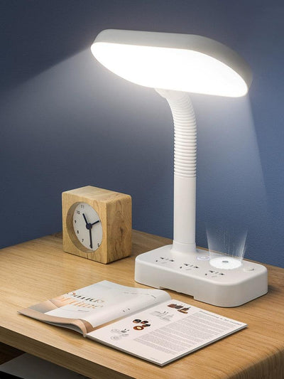 a desk reading lamp that has a usb charger and is on a table next to a book