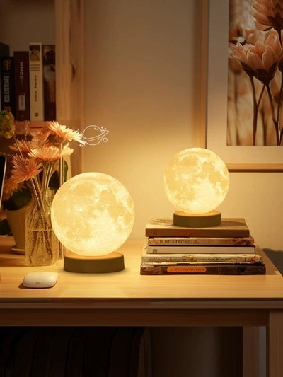 a couple of moon lamp night lights sitting on top of a table next to a bed