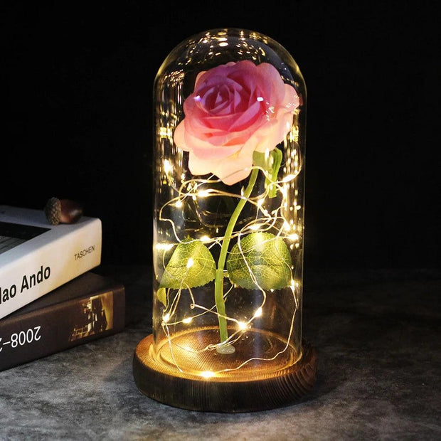 a pink rose in a glass jar with fairy lights