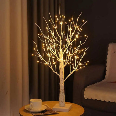 a glowing white birch tree night light bed lamp on a desk