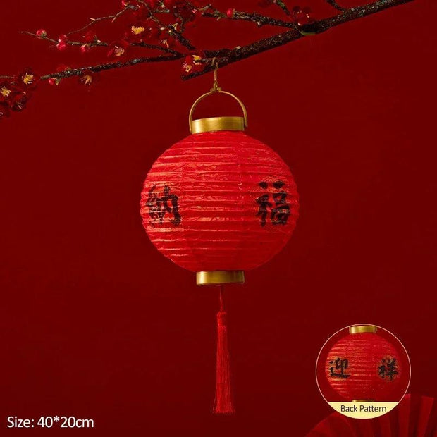 a red paper lantern hanging from a tree branch